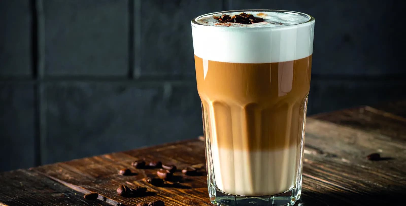 Latte Macchiato im Glas mit Milchschaum und Kaffeebohnen